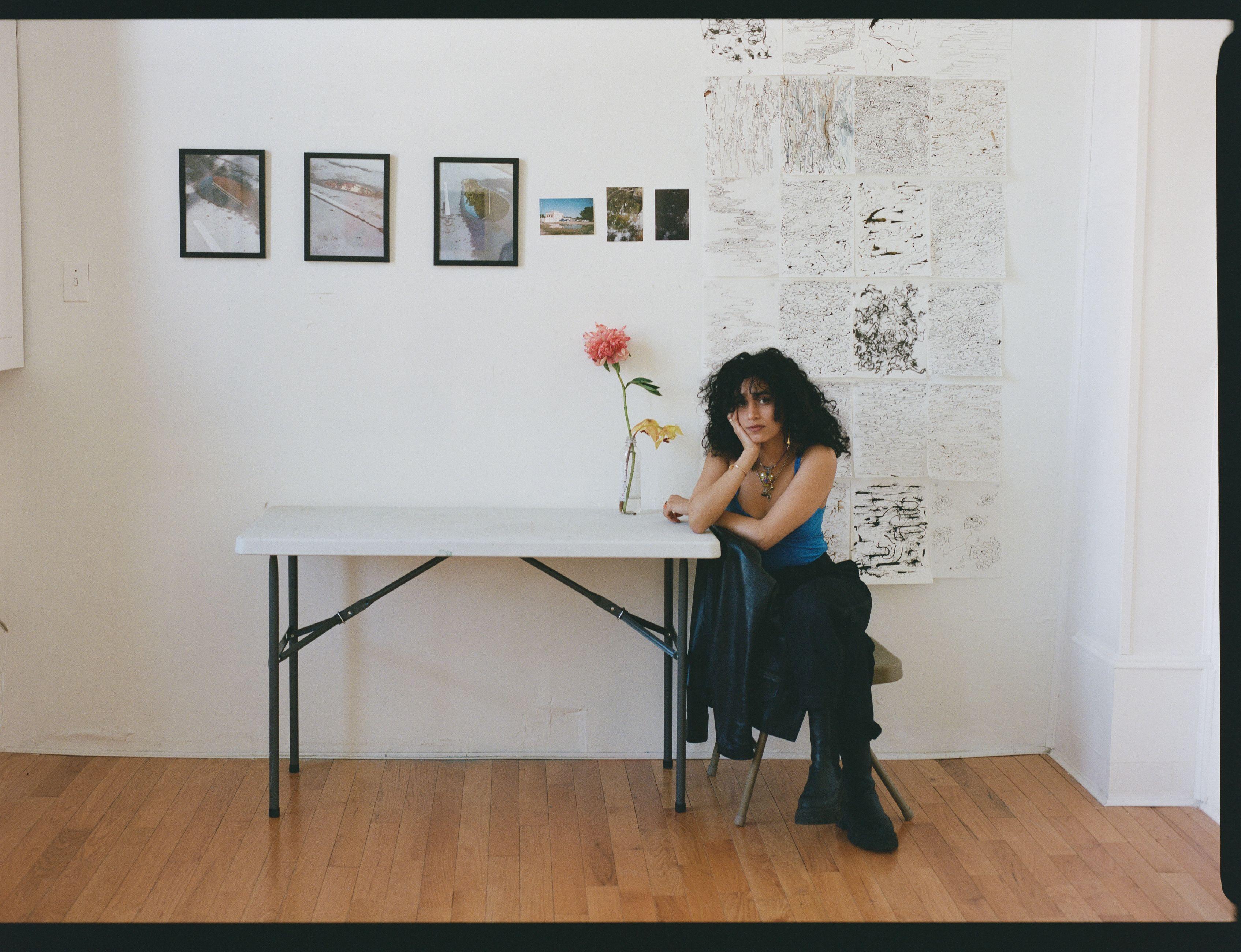 Mashael sitting at a desk in her studio.
